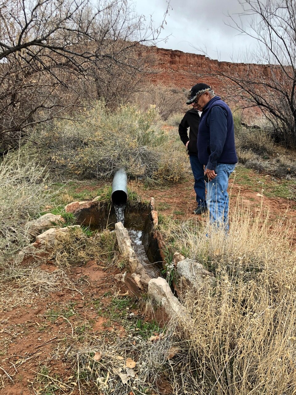 Two project partners standing next to spring on the Navajo Reservation