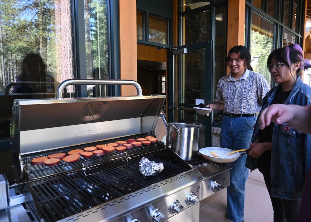 Tessa Smartt and Lance Owyhee work on their chokecherry pudding while yams cook on the grill nearby.